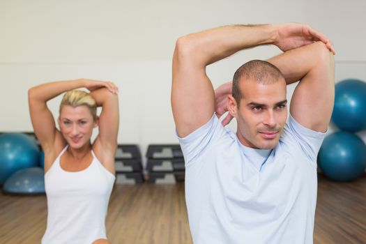 Portrait of young couple stretching hands behind back in yoga class