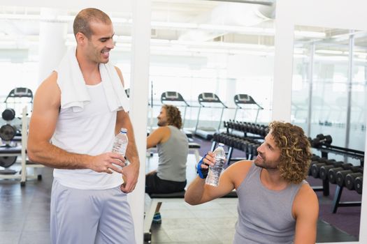 Smiling male trainer talking to fit young man at the gym