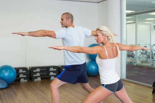 Side view of a young couple stretching hands in yoga class