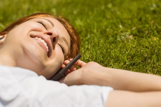 Pretty redhead calling and lying on grass at summer