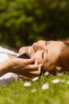 Pretty redhead calling and lying on grass at summer