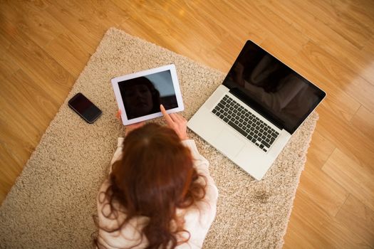 Pretty woman lying on floor using technology at Chritmas at home in the living room