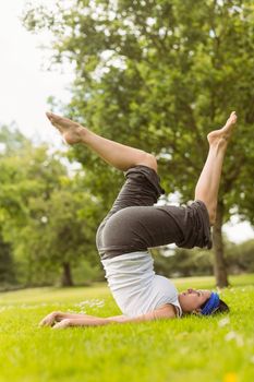 Concentrated brown hair doing yoga on grass