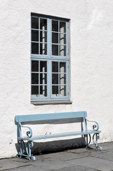 Blue bench against a white house