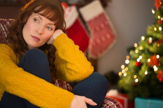 Beauty red hair thinking on the armchair at christmas at home in the living room