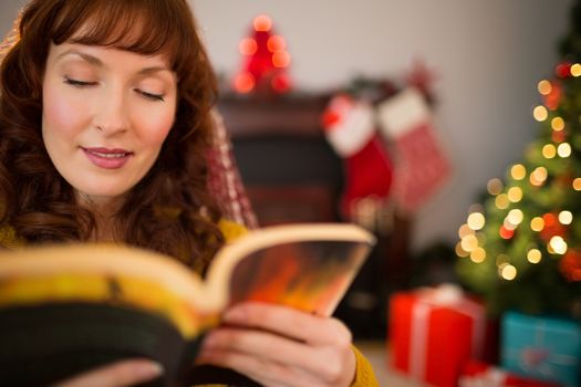 Beauty red hair reading a boo at christmas at home in the living room