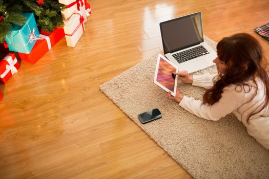 Pretty woman lying on floor using technology at Christmas at home in the living room