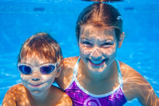 Underwater happy cute girl and boy in swimming pool