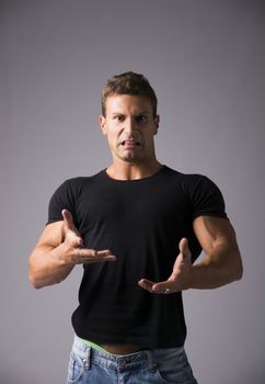 Disgusted young man with funny expression on his face looking at camera. Studio shot on grey background