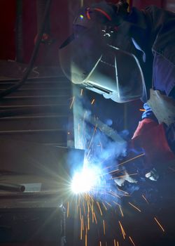 welder working with electrode at semi-automatic arc welding in manufacture production plant