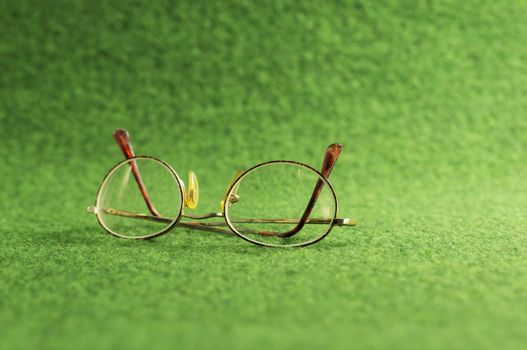 old spectacles on green background