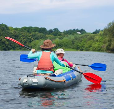 Summer vacation - Back view of Cute girl with mother kayaking on river.