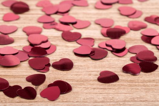 small red hearts confetti on wooden background, calentine love concept