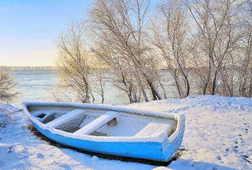 blue boat near danube river in winter time