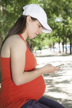 pregnant young woman with red shirt touching smartphone at a street in Madrid Spain Europe