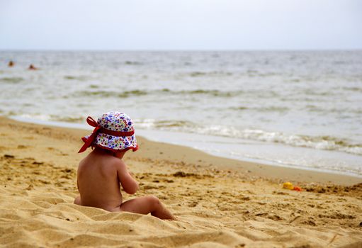 baby on beach of sea  in red hat