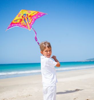 Summer vacation - Cute boy flying kite beach outdoor.