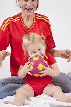 lovely blonde baby sixteen month old and mother with red shirt of Spanish soccer team
