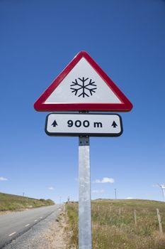 metal pole with traffic signal advice danger snow at 900 metres in rural road next to Madrid Spain Europe