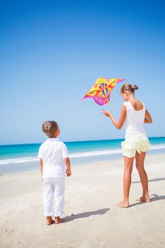 Summer vacation - Cute boy and girl flying kite beach outdoor.