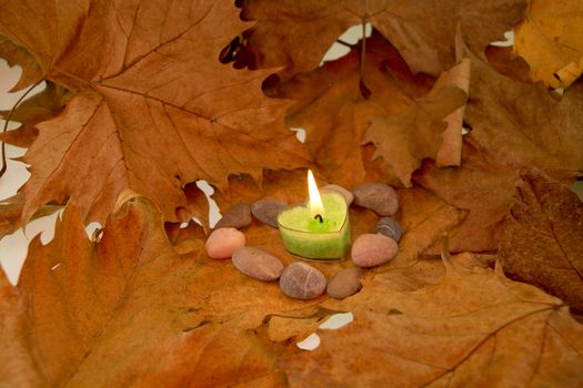 Background made of autumn leaves, heart shaped candle and stones
