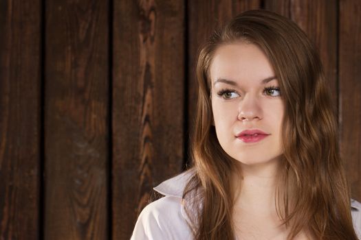 Portrait of a girl on a background of a wooden wall