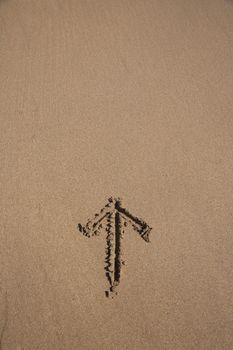 arrow drawn on brown sand ground low tide beach ocean seashore in Spain Europe