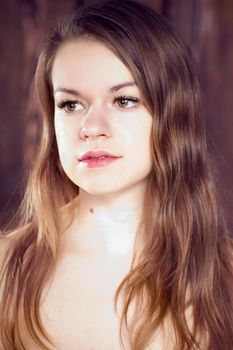 Portrait of a girl on a background of a wooden wall