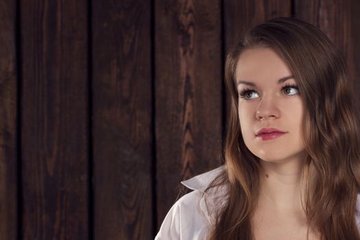 Portrait of a girl on a background of a wooden wall