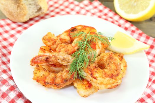 fried shrimp on a plate with lemon and dill