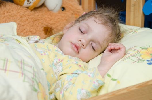 Three year old girl sweetly asleep in his crib in the nursery
