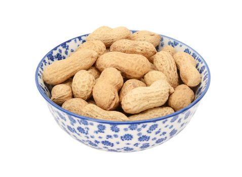 Monkey nuts in a blue and white porcelain bowl with a floral design, isolated on a white background