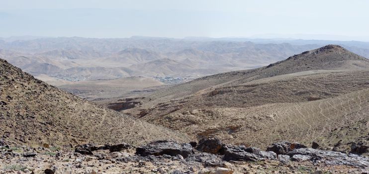 Desert landscape with far Bedouin camp on hazy day