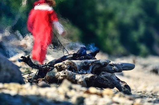 Woman in red dress near the campfire on the coast