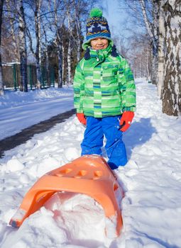 Winter, play, fun - Cute little boy having fun with sled in winter park