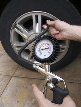 Close-up of manometer and man hands checking tire pressure with gauge.