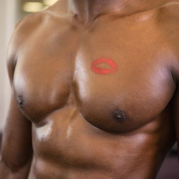 Close-up mid section of a shirtless muscular man with lipstick mark on chest