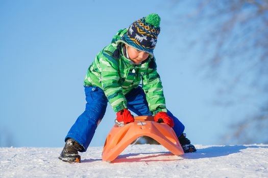 Winter, play, fun - Cute little boy having fun with sled in winter park