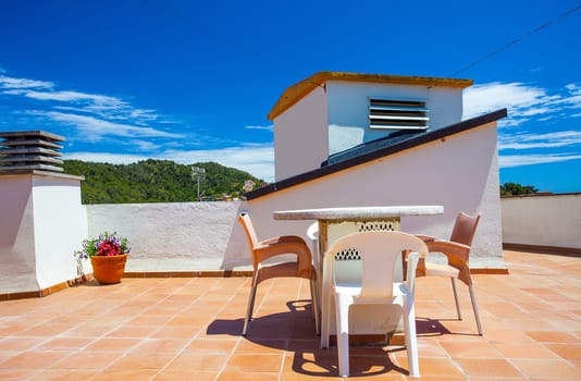 table and chairs on the roof under the open sky on a sunny day