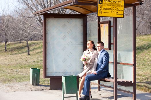 bride and groom sitting in a joke at a bus station with a motion Timetable