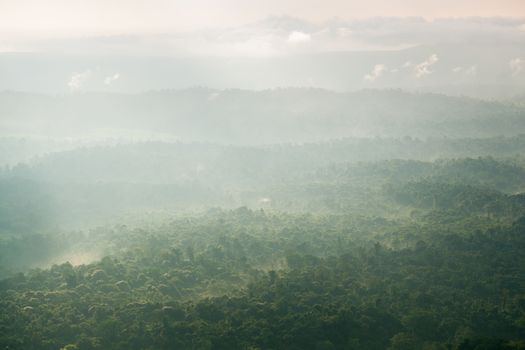 Sunlight shines through the clouds into the mountains and forests. Mist-covered mountains and trees.