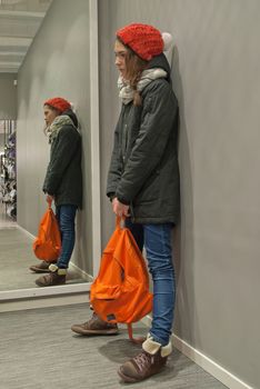 Reflection in the mirror girl in a red cap and orange backpack.