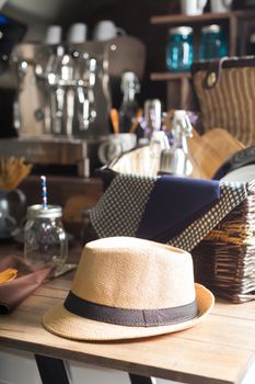 Hat resting on a wooden table. A picnic basket and a coffee maker in the background.