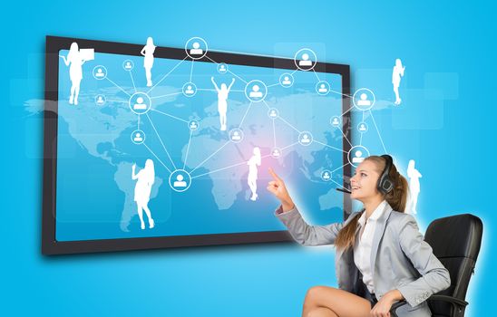 Businesswoman in headset using touch screen interface featuring world map, network of person icons and female silhouettes, on blue background