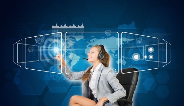 Businesswoman in headset sitting on chair using touch screen interfaces, smiling, on blue technology background