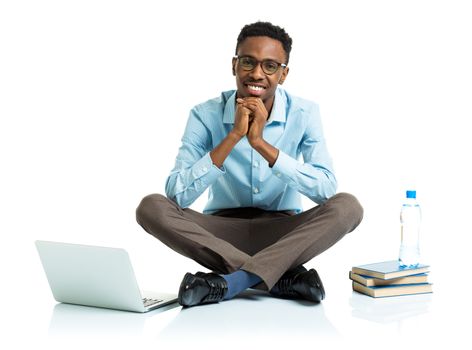 Happy african american college student sitting on white background with laptop and some books