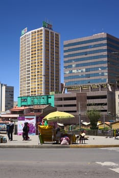 LA PAZ, BOLIVIA - OCTOBER 12, 2014: Unidentified street vender along the Camacho avenue with tall modern buildings in the back in the administrative capital on October 12, 2014 in La Paz, Bolivia 