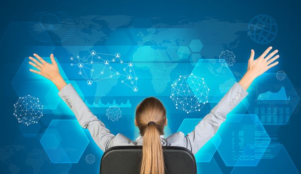 Businesswoman sitting on office chair with her hands outstretched. World map, hexagons and graphs as backdrop