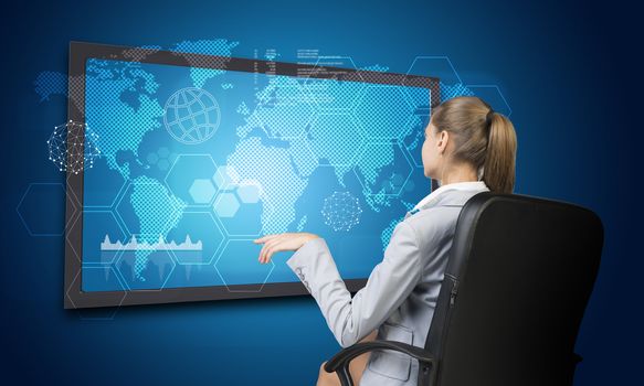 Businesswoman looking at interface with world map, graph and other elements. on blue background