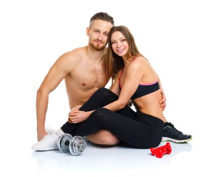 Sport couple - man and woman after fitness exercise sitting with dumbbells on the white background